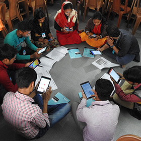 Students learning English in peer groups using tablets and smart phones.