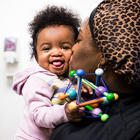 Woman holding  a happy baby - Healthy Steps
